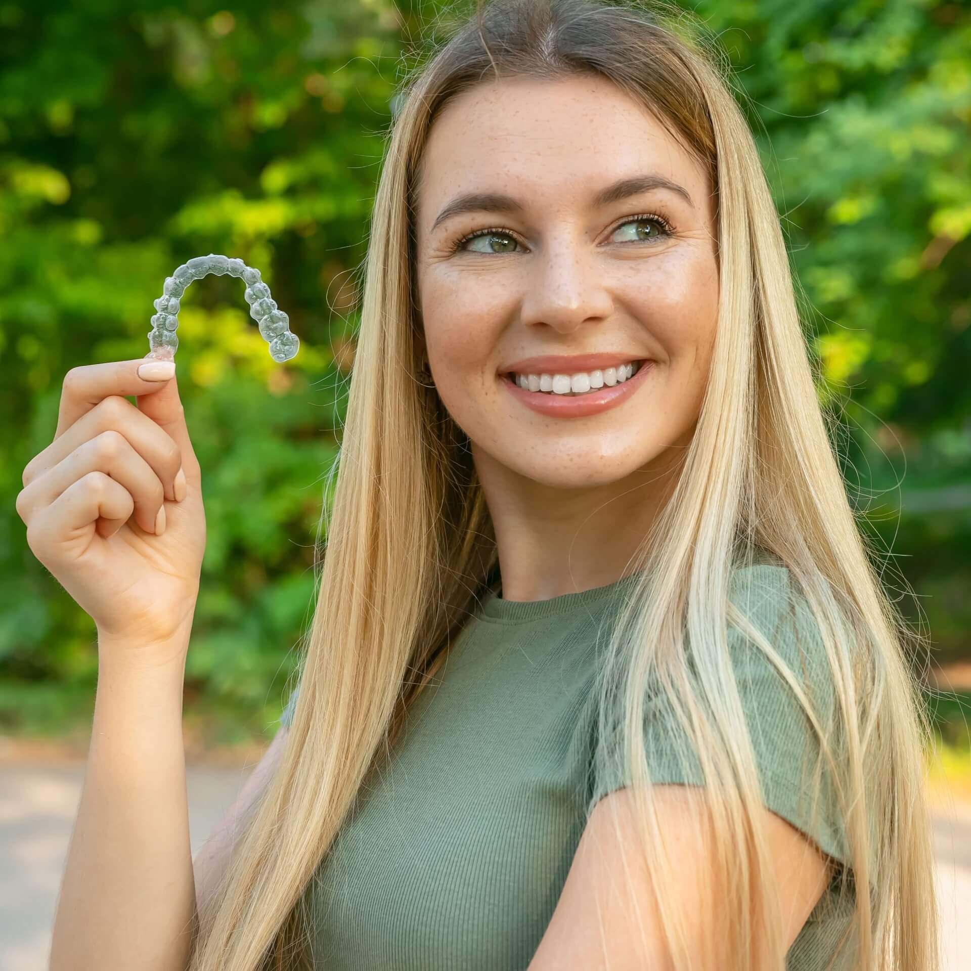 See how clear aligners work with these three easy steps A woman in a forest smiling with discreet braces