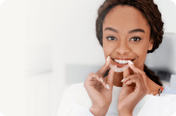 The photo of a young woman smiling with aligners on her hands
